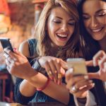 Two young women browsing online and smiling