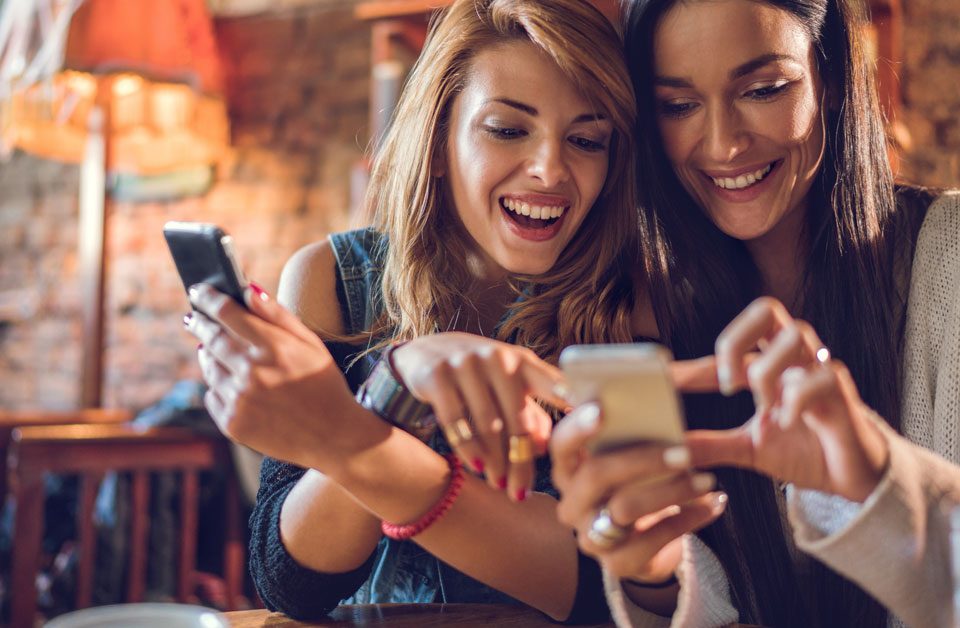 Two young women browsing online and smiling