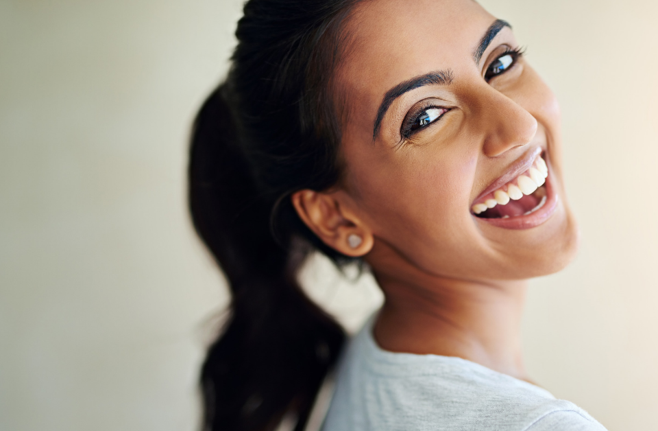 Smiling woman with pony tail looking back over her shoulder