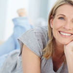Happy woman lying on her stomach resting face in one hand