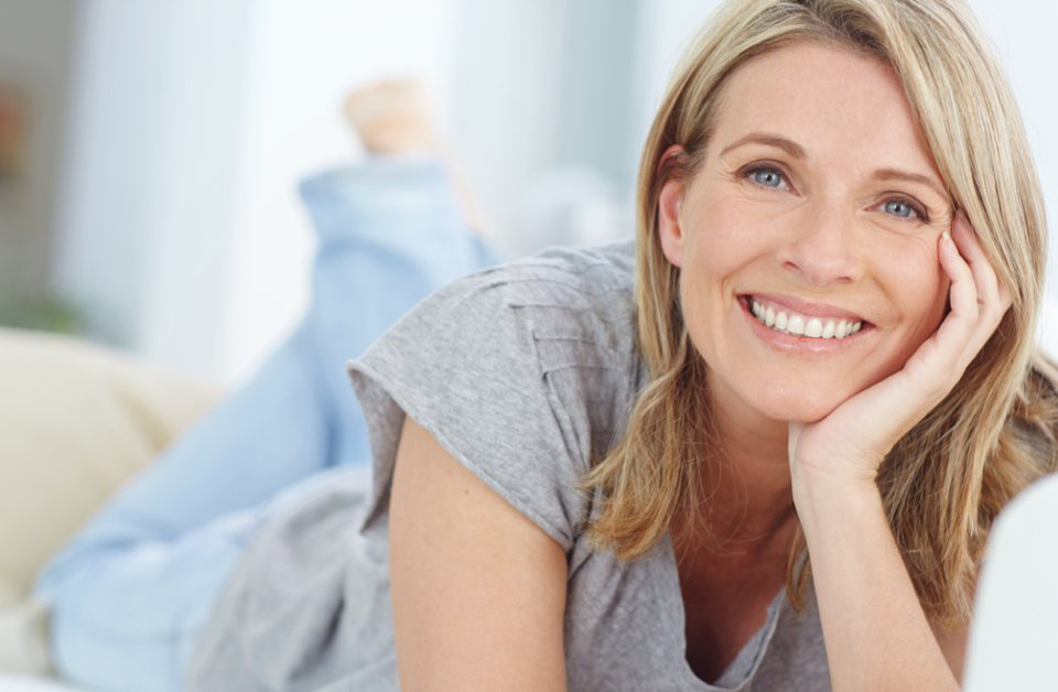 Happy woman lying on her stomach resting face in one hand