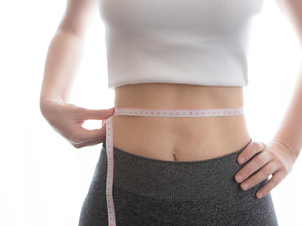 woman measuring her waist to track weight loss