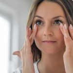 Woman with clear skin (model) holding hands up to her face.