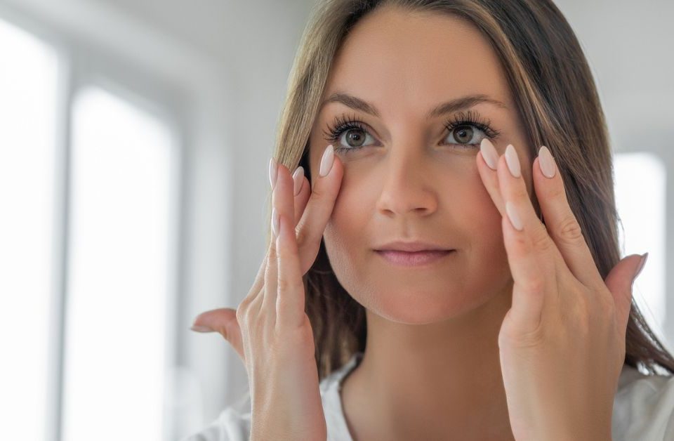 Woman with clear skin (model) holding hands up to her face.